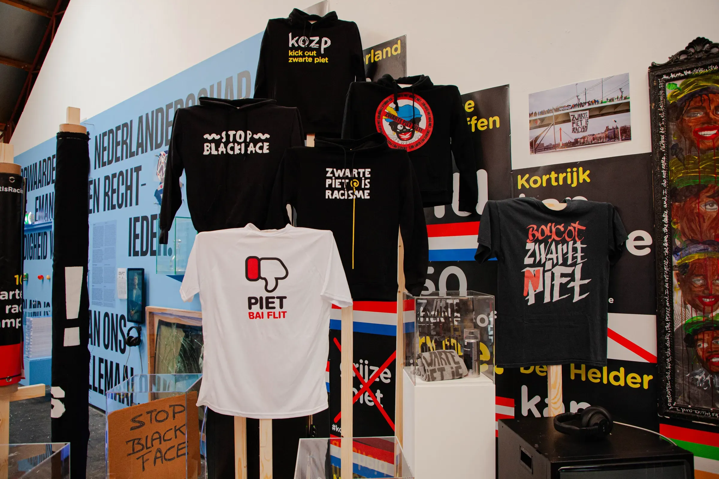 Expositie over de campagne: hoodies en shirts met 'Kick Out Zwarte Piet', 'Stop Blackface' en 'Zwarte Piet is Racisme', tussen protestborden en affiches uit tien jaar strijd.